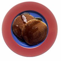 Two North American style pancakes with maple syrup.