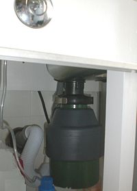 An installed garbage disposal with air switch.